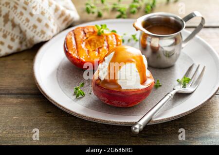 Gegrillte Pfirsiche mit Eis und Karamellsoße, sommerliches Dessert Stockfoto