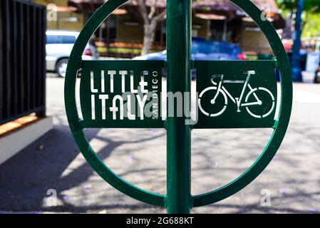 Nahaufnahme eines modernen grünen Metall-Fahrradträgers mit Little Italy-Logo und ausgeschnittener Kunst des Fahrrads auf dem Bürgersteig in der Nähe des Hafens in San Diego, CA Stockfoto