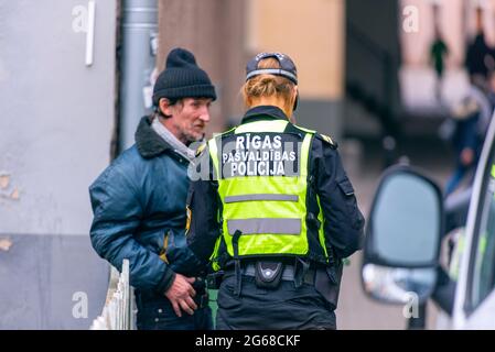 RIGA - Okt 07: Polizist der Stadtpolizei Riga und armer Mann in einer Straße von Riga, Oktober 07. 10. 2018 in Lettland Stockfoto