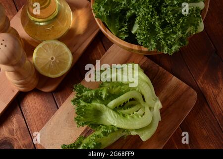 Grüne Batavia-Salatblätter auf Holzhintergrund. Bereit zum Kochen von Salat Stockfoto