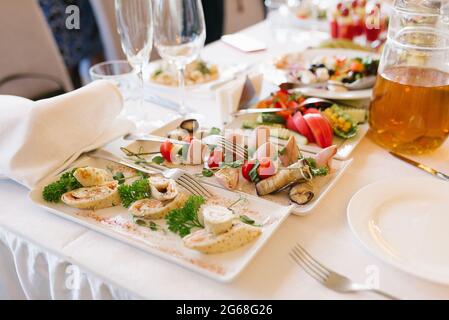 Snacks auf weißen Tellern auf einem festlichen Banketttisch bei einer Hochzeit Stockfoto