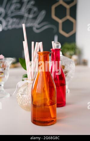 Bunte Glasflaschen mit Papphalmen für Getränke oder Cocktails auf einer Party Stockfoto