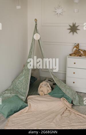 Kinderzeltzelt mit Kissen und einem weichen Spielzeughasen im Zimmer für kleine Kinder Stockfoto