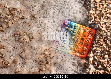 Pop ist ein Gummispielzeug auf Muscheln in geschäumtem Meerwasser. Stockfoto