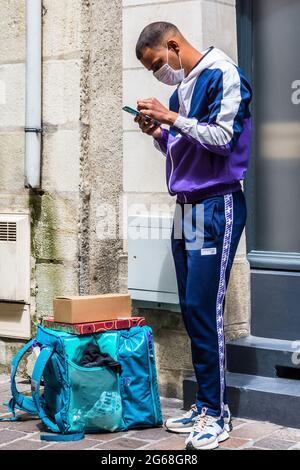 Junger Mann, der auf der Karte am Telefon nach Wegbeschreibungen sucht - Tours, Frankreich. Stockfoto