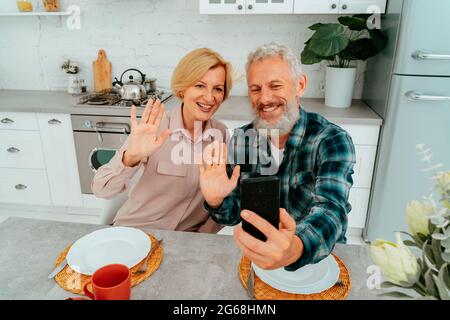 Das Paar begrüßt seine Freunde mit einem Videoanruf während des Frühstücks Stockfoto