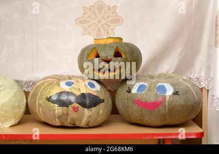 Ein Kürbis mit einer geschnitzten Halloween Jack Laterne und zwei Kürbisse mit bemalten Gesichtern und einem Lächeln zu Ehren des Herbsterntefestes Stockfoto