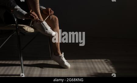 Frau zog neue weiße Leder-Sneakers an Stockfoto