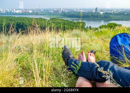 Blick auf die Beine eines verliebten Paares, das auf einem Berg liegt, mit Blick auf die Stadt Stockfoto