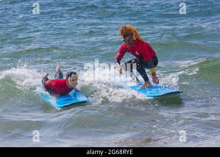 Poole, Dorset, Großbritannien. Juli 2021. Wetter in Großbritannien: bewölkt und windig mit sonnigen Intervallen an den Stränden von Poole. Die Mitarbeiter von Shaka Surf haben Spaß beim Surfen im Meer bei Branksome Chine. Quelle: Carolyn Jenkins/Alamy Live News Stockfoto