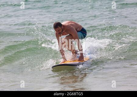 Poole, Dorset, Großbritannien. Juli 2021. Wetter in Großbritannien: bewölkt und windig mit sonnigen Intervallen an den Stränden von Poole. Surfer Surfen im Meer bei Branksome Chine. Quelle: Carolyn Jenkins/Alamy Live News Stockfoto