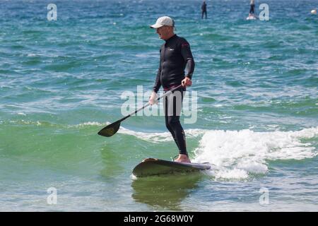 Poole, Dorset, Großbritannien. Juli 2021. Wetter in Großbritannien: bewölkt und windig mit sonnigen Intervallen an den Stränden von Poole. Paddlebarder bei Branksome Chine. Quelle: Carolyn Jenkins/Alamy Live News Stockfoto