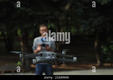 DJI-Drohnenpilot. Der junge Mann hält den Drohnencontroller in den Händen und steuert die Mavic-Drohne. Stockfoto