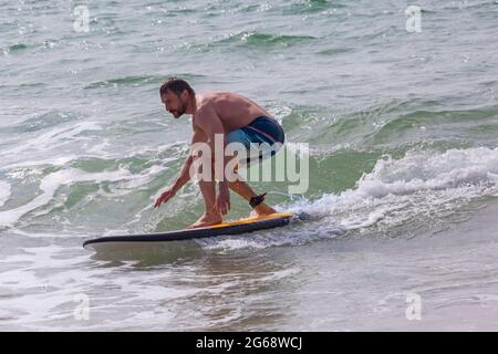 Poole, Dorset, Großbritannien. Juli 2021. Wetter in Großbritannien: bewölkt und windig mit sonnigen Intervallen an den Stränden von Poole. Surfer Surfen im Meer bei Branksome Chine. Quelle: Carolyn Jenkins/Alamy Live News Stockfoto