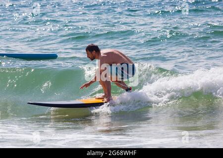 Poole, Dorset, Großbritannien. Juli 2021. Wetter in Großbritannien: bewölkt und windig mit sonnigen Intervallen an den Stränden von Poole. Surfer Surfen im Meer bei Branksome Chine. Quelle: Carolyn Jenkins/Alamy Live News Stockfoto