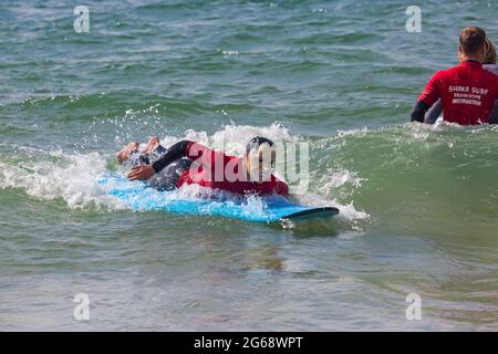 Poole, Dorset, Großbritannien. Juli 2021. Wetter in Großbritannien: bewölkt und windig mit sonnigen Intervallen an den Stränden von Poole. Die Mitarbeiter von Shaka Surf haben Spaß beim Surfen im Meer bei Branksome Chine. Quelle: Carolyn Jenkins/Alamy Live News Stockfoto