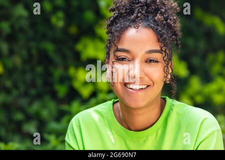 Outdoor-Porträt von schönen glücklich gemischte Rasse biracial afroamerikanischen Mädchen Teenager weibliche junge Frau lächelnd mit perfekten Zähnen trägt einen grünen t Stockfoto