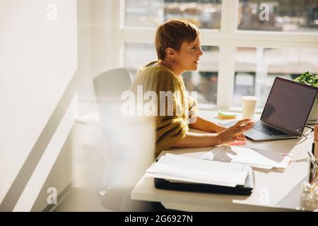 Geschäftsfrau sitzt an ihrem Schreibtisch und redet mit jemandem. Geschäftsfrau an ihrem Arbeitsplatz. Stockfoto