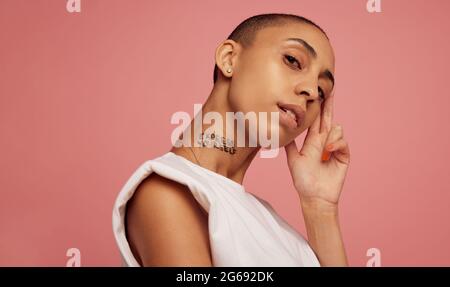 Pfrtrait einer Frau mit Express Yourself auf ihrem Hals geschrieben. Junge androgyne Frau vor rosa Hintergrund. Stockfoto