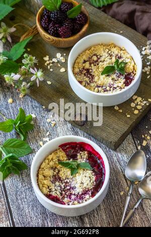 Brombeere glutenfrei backen. Hausgemachtes Dessert. Brombeeren bröckeln auf einem rustikalen Holztisch. Stockfoto