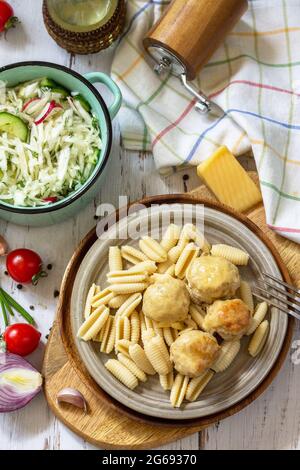 Italienische Pasta, Mittagessen mit Keto-Diät. Spaghetti mit Fleischbällchen in Käsesauce und frischem Gemüsesalat auf einem Holztisch. Stockfoto