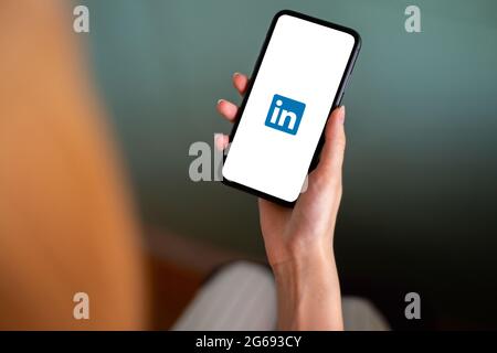 Riga, Lettland - 3. Juli 2021: Frau mit Mobiltelefon und LinkedIn-Logo auf dem Bildschirm Stockfoto