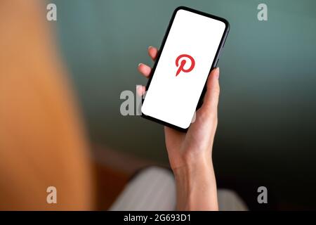 Riga, Lettland - 3. Juli 2021: Frau mit Mobiltelefon und Pinterest-Logo auf dem Bildschirm Stockfoto