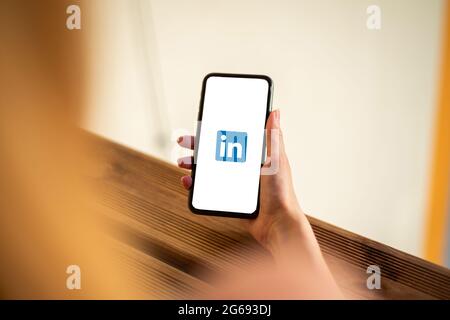 Riga, Lettland - 3. Juli 2021: Frau mit Mobiltelefon und LinkedIn-Logo auf dem Bildschirm Stockfoto