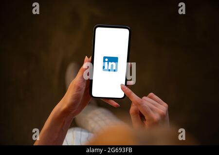 Riga, Lettland - 3. Juli 2021: Frau mit Mobiltelefon und LinkedIn-Logo auf dem Bildschirm Stockfoto