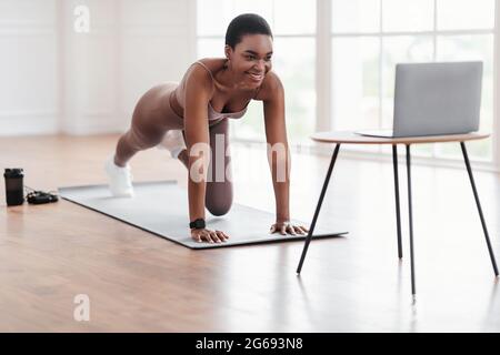 Fröhliche Afro-Frau Beim Training Von Cross Body Mountain Kletterern Stockfoto