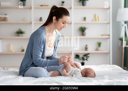 Konzept Der Kinderbetreuung. Glückliche Junge Mutter Macht Gymnastik Für Ihr Neugeborenes Baby Stockfoto