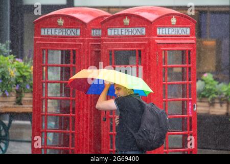 Während eines Regenguts in Covent Garden, London, untersteht ein Mann unter einem Regenschirm, da Teile Großbritanniens von starken Regenfällen und Gewittern getroffen werden. Bilddatum: Sonntag, 4. Juli 2021. Stockfoto