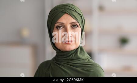 Muslimische Frau Mittleren Alters, Die Hijab Trägt Und Die Kamera Im Inneren Posiert Stockfoto