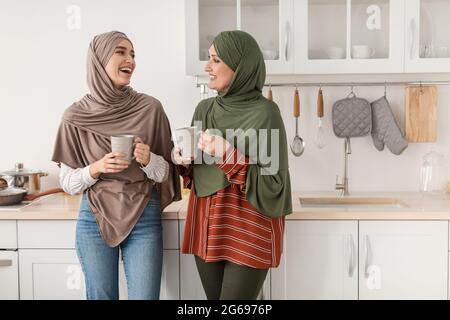 Ältere Muslimische Mutter Und Erwachsene Tochter Genießen Kaffee In Der Küche Stockfoto