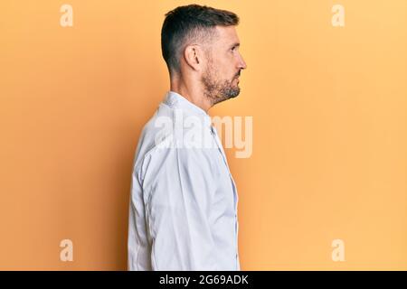 Ein gutaussehender Mann mit Bart trägt eine professionelle Koch-Uniform, die zur Seite schaut, entspannt die Profilpose mit natürlichem Gesicht und einem selbstbewussten Lächeln. Stockfoto