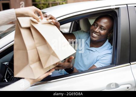 Glücklicher afroamerikanischer Mann Fahrer, der Papiertüten nahm Stockfoto