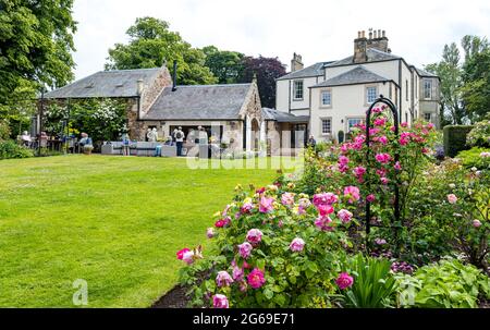 East Lothian, Schottland, Großbritannien, 4. Juli 2021. Scotland's Garden Scheme neuer Garten eröffnet: Shane Corstorphine, ehemaliger CFO von Skyscanner und begeisterter Gärtner, hat 4 Jahre damit verbracht, die Gärten von Camptoun House zum ersten Mal für die Eröffnung vorzubereiten, um Geld für einen ummauerten Garten in Gilmerton zu sammeln. Es gibt einen Küchengarten, ummauerten Garten, Obstgarten und Feenpfad. Über 400 Menschen besuchten den Garten über das Wochenende trotz heftigem Regen gestern. Im Bild: Im ummauerten Garten mit Blick auf das georgische Landhaus genießen die Menschen Tee und Kaffee Stockfoto