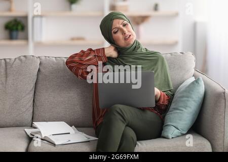 Reife Muslimische Geschäftsfrau, Die Den Hals Berührt Und Schmerzen Mit Einem Laptop In Der Halle Hat Stockfoto