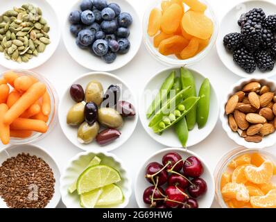 Draufsicht auf mehrere kleine Gerichte, gefüllt mit verschiedenen Arten von frischen ganzen rohen Lebensmitteln. Stockfoto