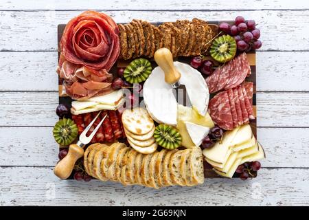 Blick von oben auf ein Fleisch- und Käseplatte auf einem hellen Holztisch. Stockfoto