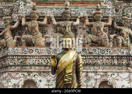 Goldene Buddha-Figuren vor der alten Pagode, riesige Schutzstatuen mit keramischen Mosaikfliesen im Hintergrund. Wat Arun. Bangkok, Thailand. Stockfoto