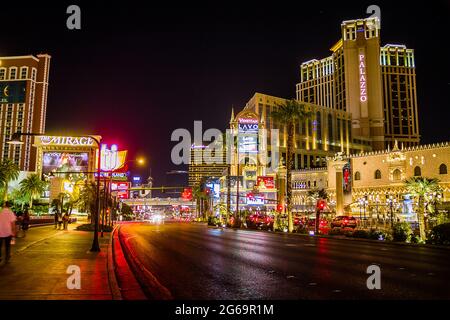 Der Palazzo und das Mirage auf dem Strip in Las Vegas bei Nacht mit Menschen, die auf der Straße spazieren Stockfoto