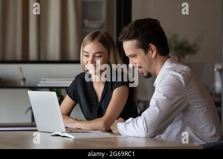 Glückliche Kollegen Geschäftsmann und Geschäftsfrau mit Laptop, die zusammen arbeiten Stockfoto
