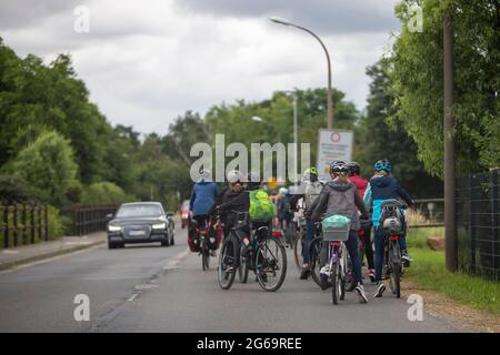 Meckenheim, NRW, Deutschland, 06 30 2021, Gruppe von Kindern, die auf einer Landstraße Fahrrad fahren. Autos fahren auf der Straße Stockfoto