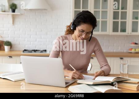 Lächelnde junge Frau, die an Online-Bildung beteiligt ist. Stockfoto