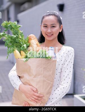 Junge Frau im Freien mit einer Tasche mit Lebensmitteleinkäufen. Stockfoto