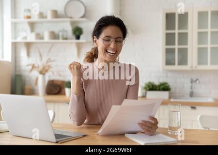 Emotionale glückliche junge Frau beim Lesen von Papier mit guten Nachrichten. Stockfoto