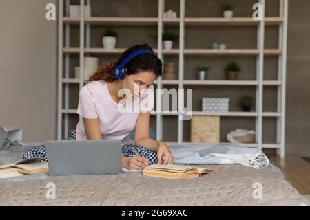 Intelligente tausendjährige hispanische Frau, die allein im Schlafzimmer studiert. Stockfoto