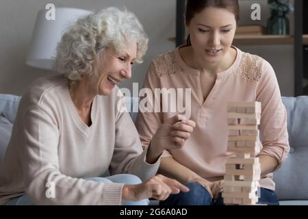 Lachende, reife Mutter spielt in einem stürzenden Turm mit einer erwachsenen Tochter Stockfoto