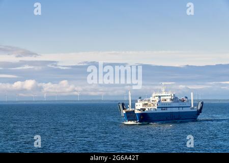 Die kleine Autofähre verkehrt zwischen dem Virtsu-Hafen Estland und der Insel Saaremaa an der Ostsee. Ruhiges Meer und blauer Himmel mit weißen Wolken. Stockfoto